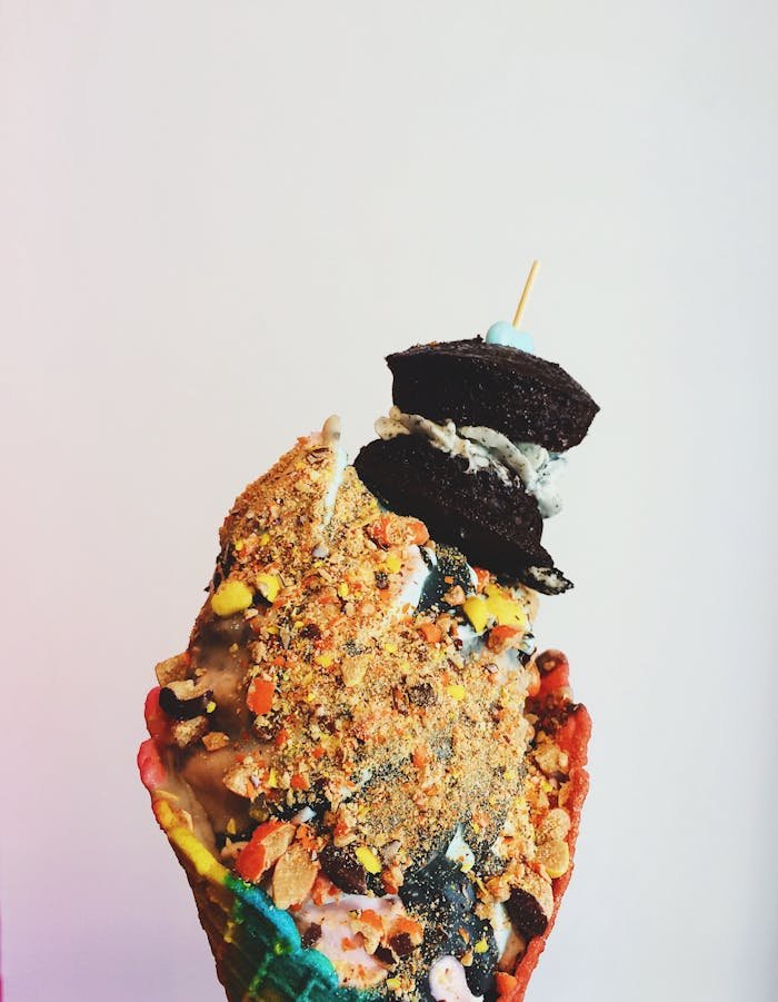 pexels-photo-1006190 A vibrant ice cream cone stacked with colorful toppings and cookies, perfect for dessert lovers.