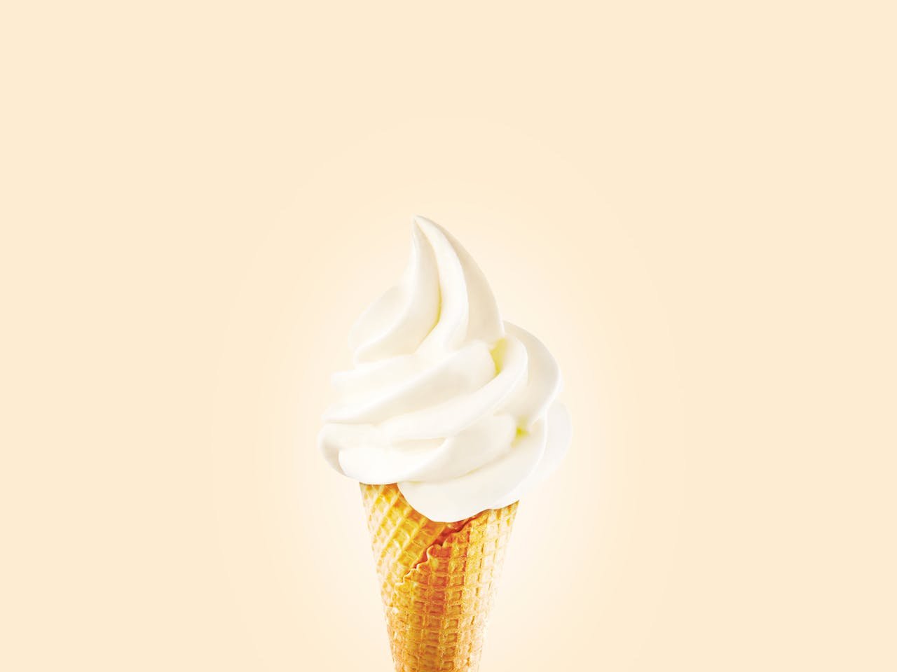 about-02 Close-up of a creamy soft serve ice cream cone on a bright background.