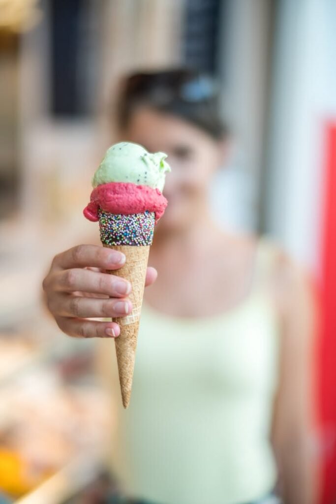 pexels-photo-1352272 Woman holding a vibrant ice cream cone topped with sprinkles, creating a refreshing summer treat.