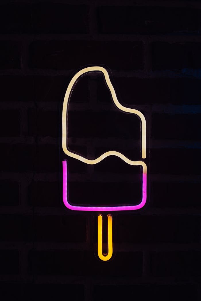 about-06 Vibrant neon ice cream sign glowing against a dark brick background, creating a modern and playful vibe.